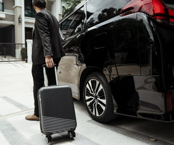Businessman pulling luggage wheel to a car traveling to airport.
